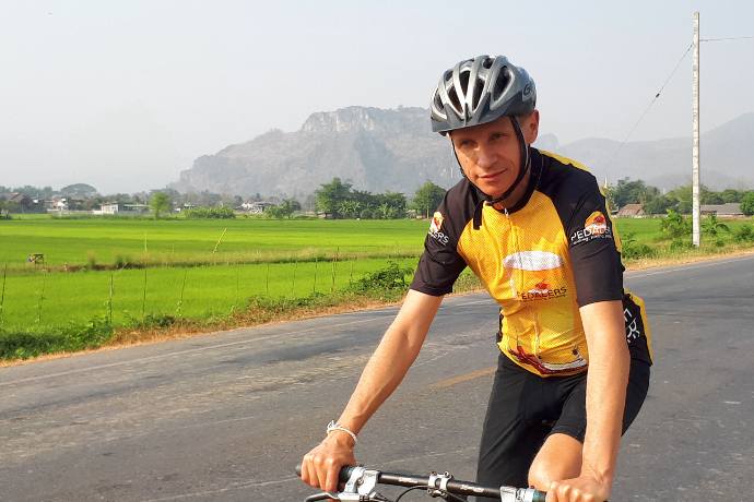 bicyclist riding past green rice paddies